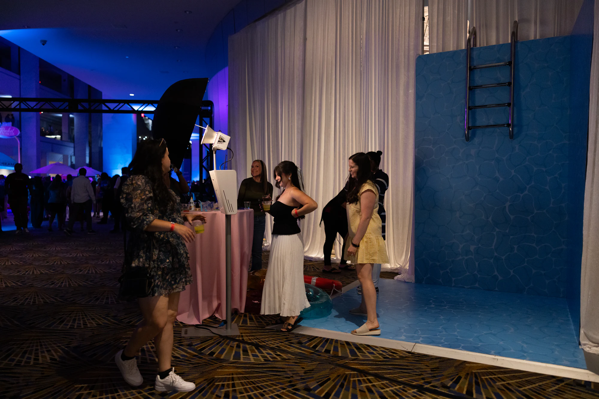 Guests stepping into the pool set, the booth and light standing beside it at The Dream Party: Rocket at 40